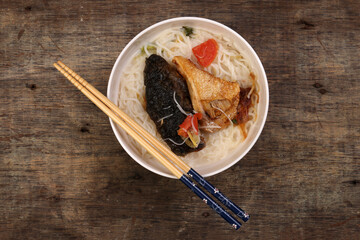 Fish head noodles vermicelli milk soup in white bowl chopstick on rustic wooden background