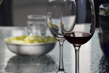 Two wine glasses on a table with party food in the background