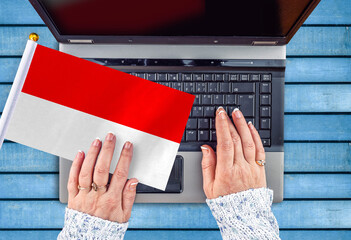 woman hands and flag of Indonesia on computer, laptop keyboard
