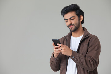 A YOUNG MAN SMILING WHILE USING MOBILE PHONE	