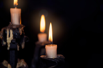Burning candles in a candlestick on a dark background.