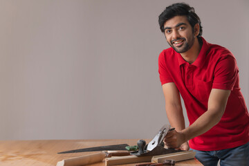 A YOUNG CARPENTER SMILING AT CAMERA WHILE WORKING	