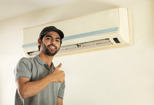 A YOUNG PROFESSIONAL HAPPILY SMILING AFTER REPAIRING AIR CONDITIONER	