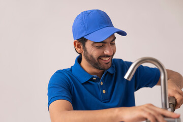 A PLUMBER HAPPILY REPAIRING A BROKEN TAP	