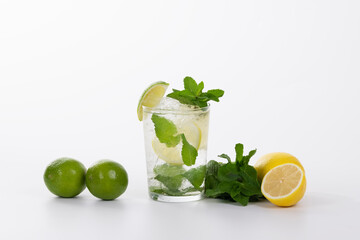 view of a refreshing mojito cocktail surrounded by limes, lemons and fresh mint leaves