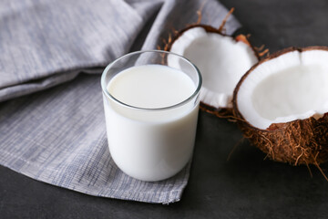 Glass with tasty coconut milk on dark background