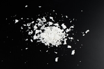 a pile of poured white artificial synthetic snow on a black background