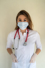 Female nurse in white uniform and medical mask standing in clinic