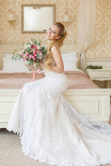 Pretty young Bride. Blonde-haired woman with wedding hair-style with a long tail. Boudoir morning of the bride. Looking to the camera