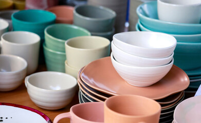Close up of empty ceramic bowls and plates on wooden table in market