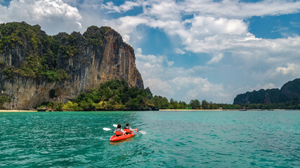 Fototapeta na wymiar Family kayaking in sea, mother and daughter paddling in kayak on tropical sea canoe tour near islands, having fun, active vacation with children in Thailand, Krabi 