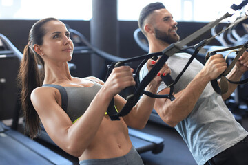 Young couple on body training with trx in gym.