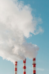 Dense white smoke from industrial chimneys against a clear blue sky - an ecological disaster