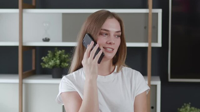 Young business woman having conversation on mobile phone at home office. Closeup smiling girl answering phone call.