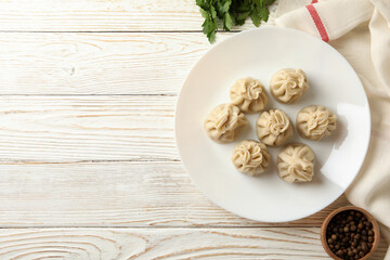Concept of tasty lunch with plate of khinkali on white wooden background