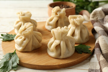 Concept of tasty lunch with board of khinkali on white wooden background