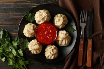 Concept of tasty lunch with plate of khinkali and sauce on wooden background