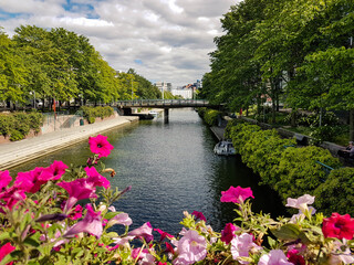 Fototapeta na wymiar Canal, bridge, boats and trees with pink flowers on foreground.