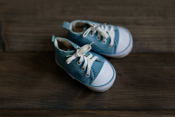 Blue children's sneakers on a brown wooden background. Selective focus