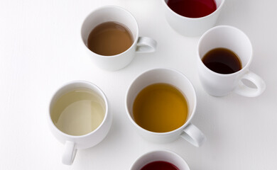 Different types of tea for ceremony. Set of cups with tea. White cups with different types of tea on a white background.