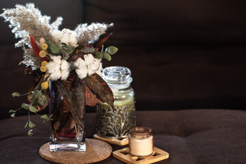 Floral composition with dried plants and decorative candles.