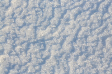 Beautiful winter background with snowy ground. Natural snow texture. Wind sculpted patterns on snow surface.