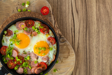 Fried eggs with sausages, tomatoes and vegetables.