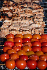 Cherry tomatoes and meat on skewers over an open fire close up. Barbecue