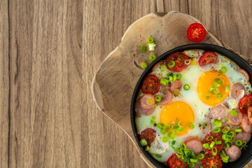 Fried eggs with sausages, tomatoes and vegetables.