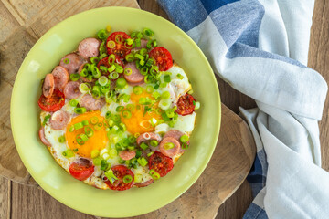 Fried eggs with sausages, tomatoes and vegetables.