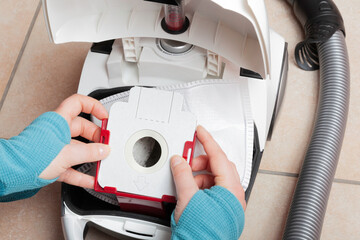 Woman changing a vacuum cleaner bag