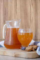 Traditional Russian cold rye drink Kvass in a glass and a jug on a wooden table.
