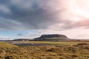 Small runway, Strandhill airport, county Sligo, Ireland, famous Knocknarea hill in the background, warm sunny day, Beautiful cloudy sky. Nobody. Nature scene