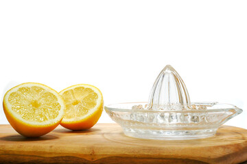 Freshly cut yellow lemon and glass juicer on a wooden board. White background.