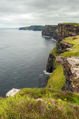 Beautiful view on Cliff of Moher, county Clare, Ireland. Popular tourist landmark and destination with epic nature landscape.Calm Atlantic ocean and cloudy sky