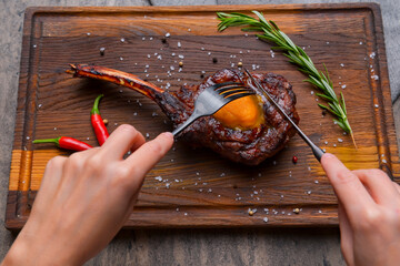 Barbecue tomahawk steak with spices served on a rustic wooden board over wooden background.