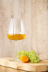 Amber or white wine with fruit. Poured glass with wine surrounded by grapes, peaches and pears