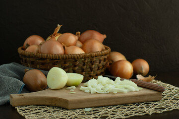 Onions on a dark background. Onions in a wicker basket. Onions chopped on a cutting board during cooking. There is space for text.