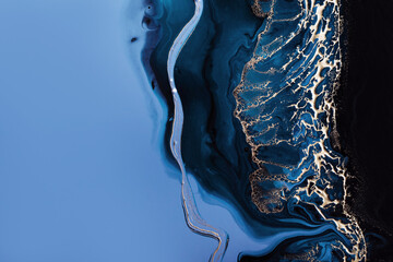Acrylic Fluid Art. Dark blue waves in abstract ocean and golden foam. Marble effect background or texture