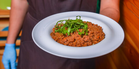 Waiter serving pasta bolognese in restaurant or diner. Eating out concept. Serving of Italian spaghetti.