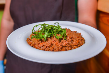 Waiter serving pasta bolognese in restaurant or diner. Eating out concept. Serving of Italian spaghetti.