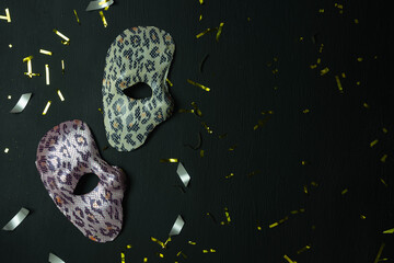 Table top view aerial image of beautiful colorful carnival festival background.Flat lay accessory object the several mask & decor confetti on modern black wooden at home office desk studio.copy space.