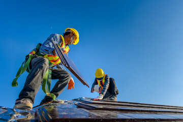 Two male workers wearing safety clothes Installing the roof tile house That is a ceramic tile roof On the construction site - obrazy, fototapety, plakaty