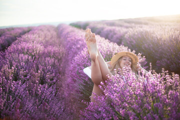 Close-up of the legs of beautiful blond woman with long curl hair relax in the purple field with...