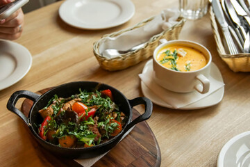 yellow cheese soup stands next to hot fried meat in a pan