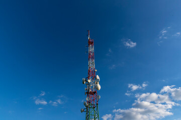 Broadcast wireless signal transmission tower in the background of blue sky and white clouds.