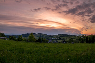 Naklejka na ściany i meble Landscape full of hills and mountains with clouds and blue sky with sun during colorful sunset Beskydy region.