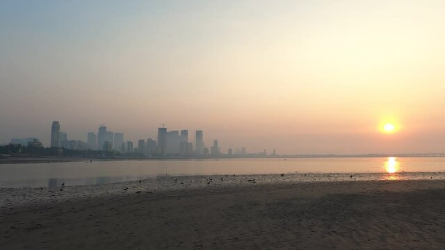 4K Wide Angle Real time footage of Mumbai Skyline on a smoggy hazy evening during sunset. Dadar beach, Mumbai, Maharashtra, India. GH010731.