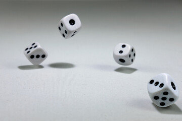  White playing dice cubes in motion on the white canvass surface, selective focus