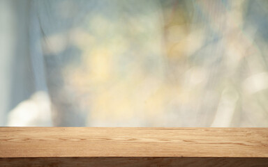 Empty wood table top seen from blur window with pine tree in snowfall of morning winter season. For a great product on the background concept.
